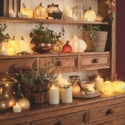 Lot De 8 Citrouilles Lumineuses En Verre à La Patine Blanche -Éclairage Domestique une selection de citrouilles lumineuses de differentes tailles sur une etagere